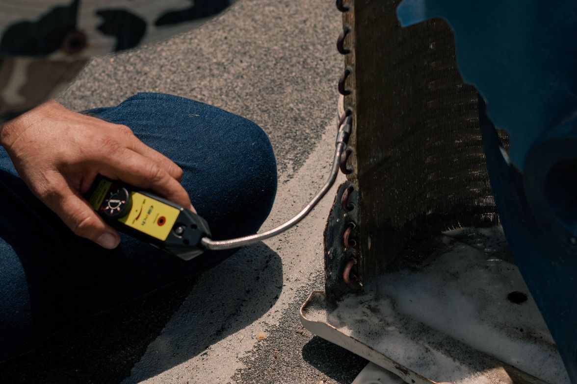 Close-up of a technician's hands servicing an outdoor air conditioning condenser on a sunny day.