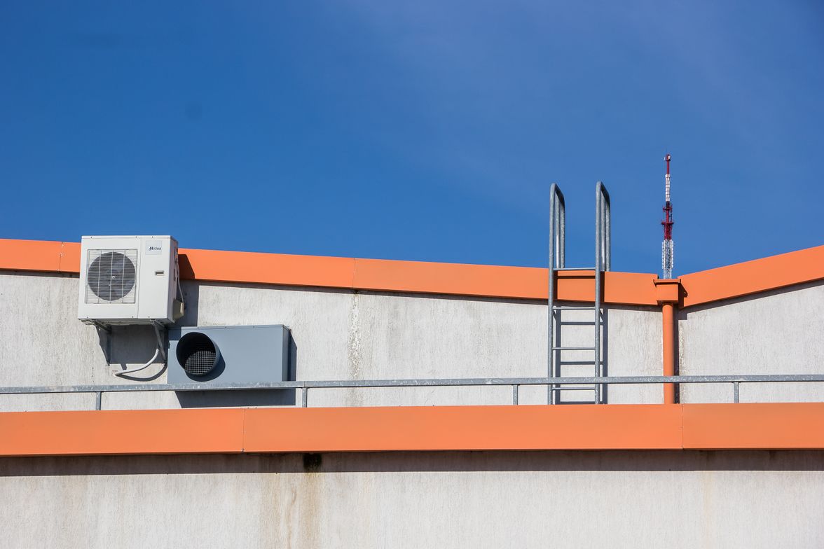 Packaged rooftop HVAC unit and access ladder on a commercial building roof.